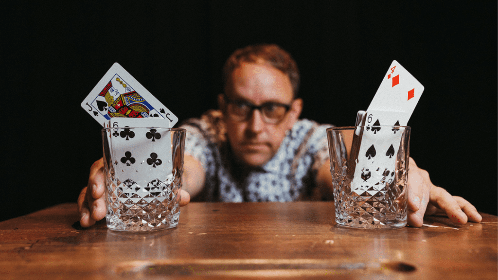 Magician Justin 'Bro' Gilbert holding glasses with cards in them