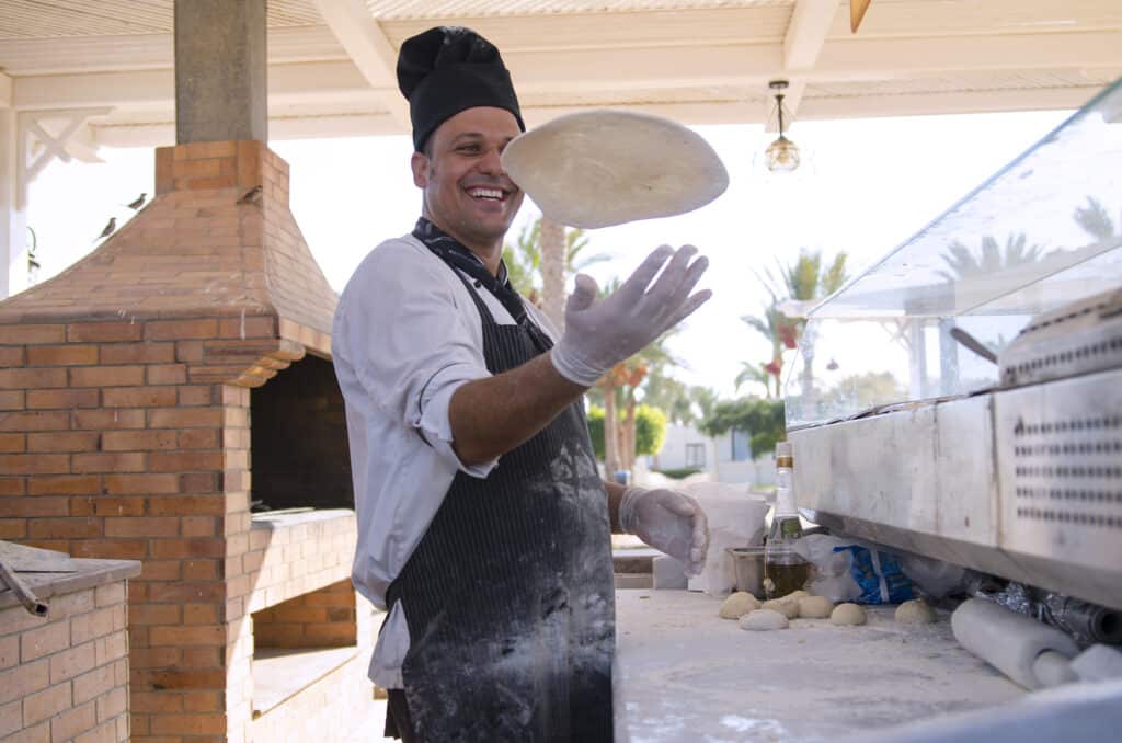Man throwing pizza dough into the air