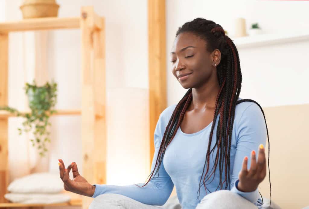 Meditation. Peaceful African American Woman Meditating Sitting In Lotus Yoga Pose In Bed Relaxing At Home. Selective Focus